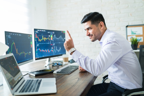 Junger Trader handelt an drei Bildschirmen. Professeionelle Handelsplattform, übersichtlich und benutzerfreundlich. Erfahrener Trader mit eigener Strategie die zum Erfolg führt. Handel mit CFDs, ETFs, Aktien, Fonds, Kryptowährungen, Forex und vieles mehr. Optimaler Arbeitsplatz. Optimistisch bleiben und Chancen erkennen. Chart- und Fundamentalanalyse einsetzen um besten Zeitpunkt für Trades auszumachen.